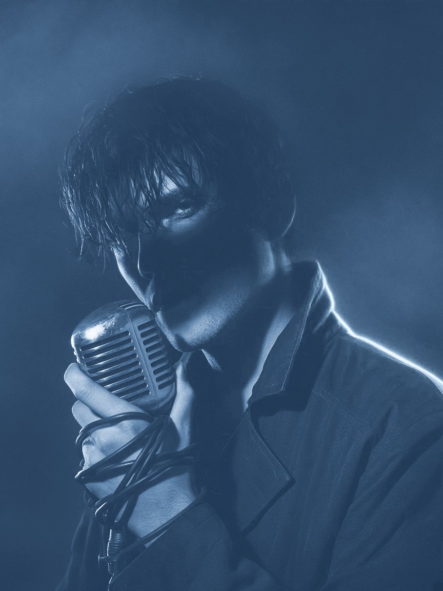 AoM holding a vintage microphone, face in shadow